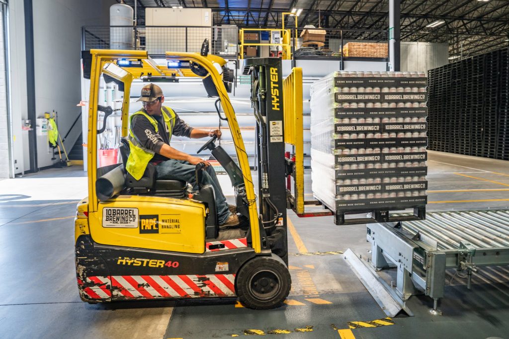Forklift operator backs up with a loaded pallet.