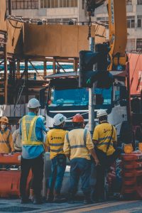 Four employees observe machine from a save distance.