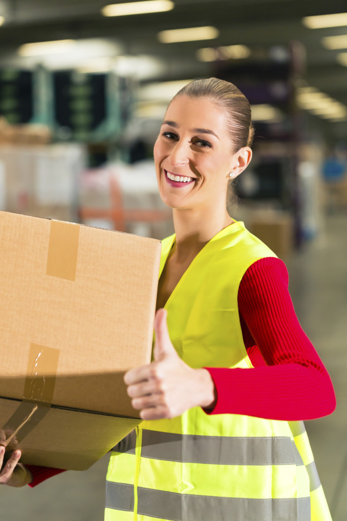 Warehouse employee smiles and gives a thumbs up.