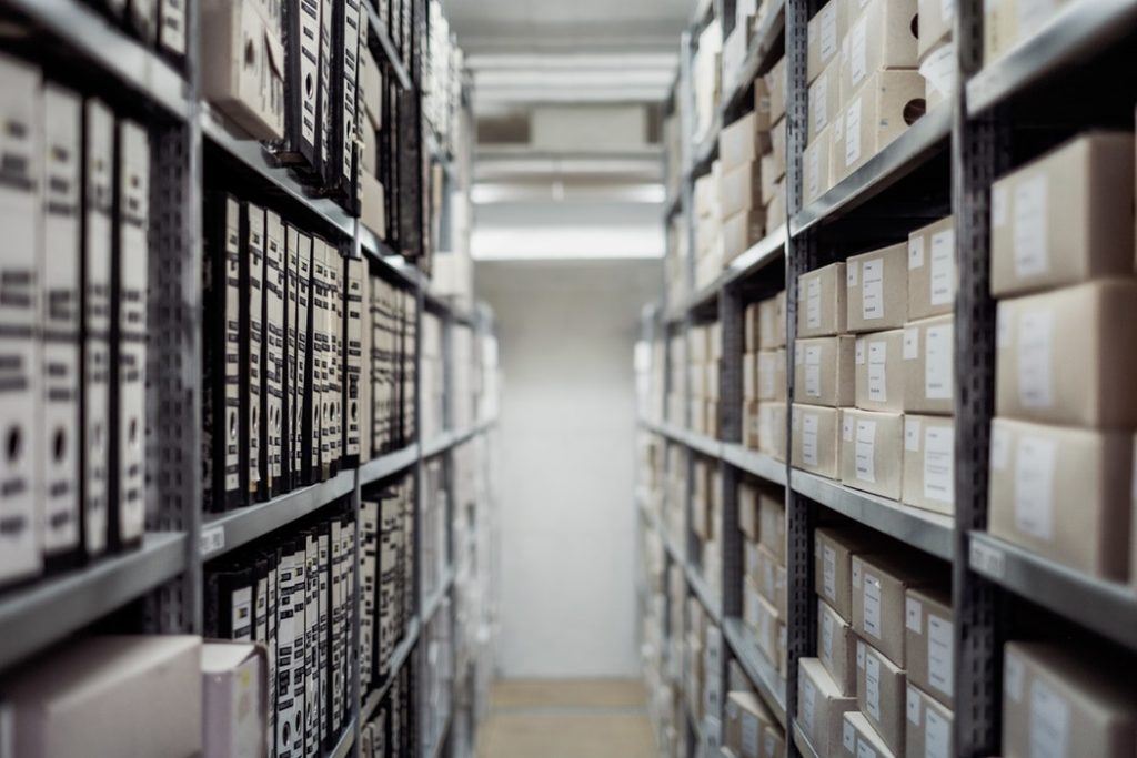 Aisle of metal shelving with boxes and materials stored on the shelves.