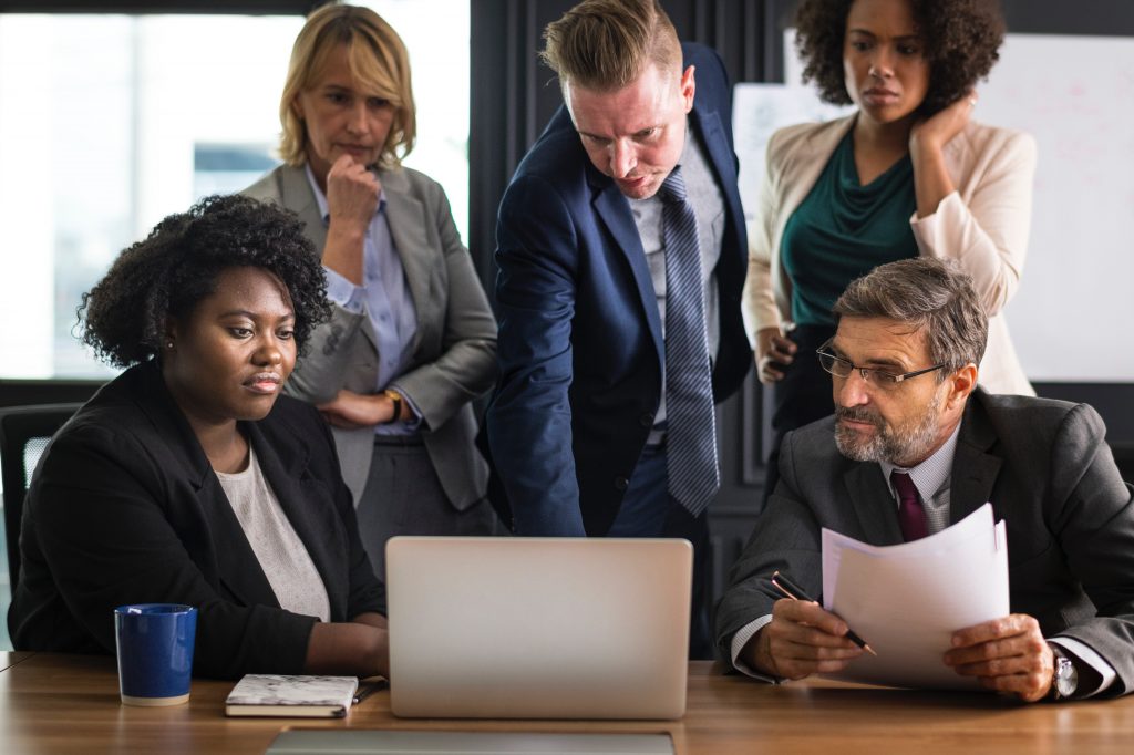 Businesspeople gaze intently at a laptop screen.