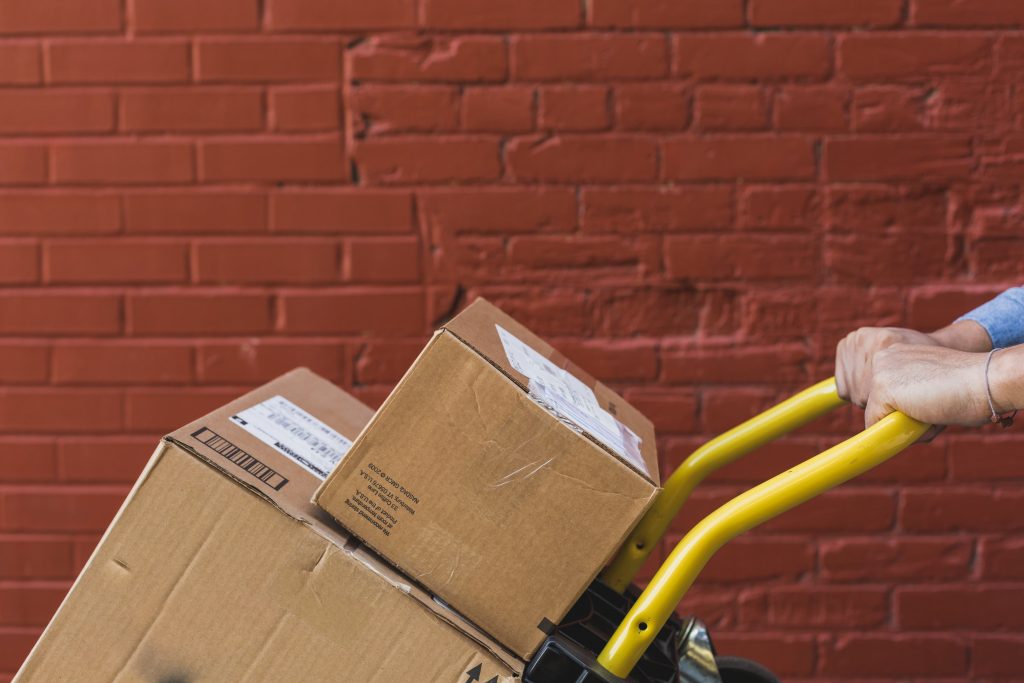 Closeup of employee pushing a handtruck loaded with boxes.