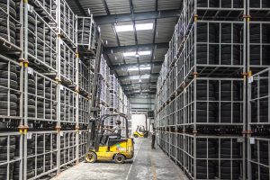 Forklift operator puts away stack rack of product.