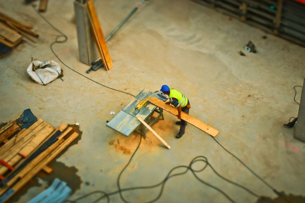 Birds-eye-view of construction worker cutting wood on a table saw.