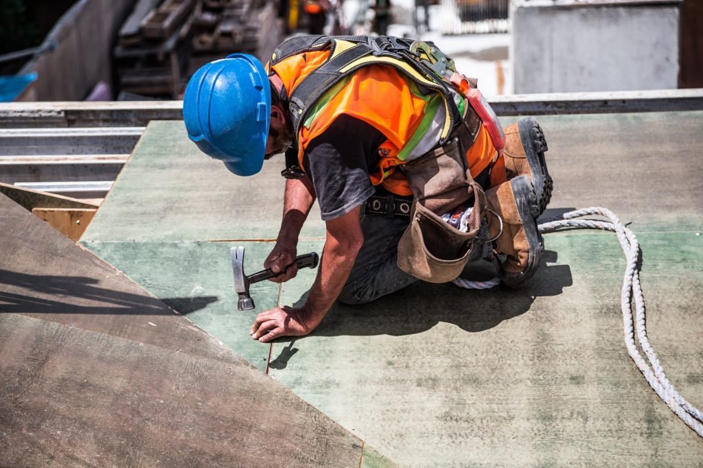 Construction worker hammers in wood decking on a project.