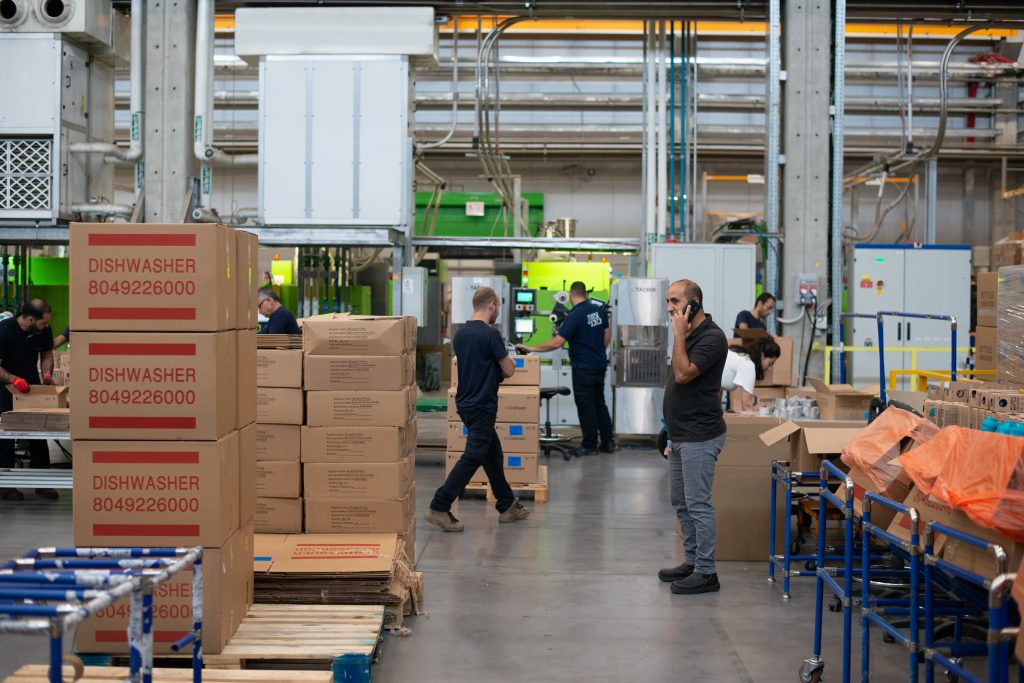 Manager takes a phone call as warehouse workers fulfill orders.