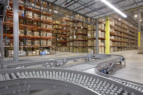 An automated conveyor system in a warehouse with shelves of boxes in the background