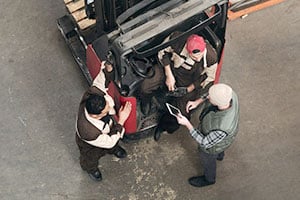 Employee meeting with other employees around the forklift to train them. 