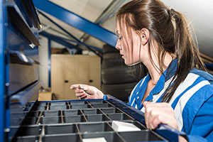 Warehouse worker looks for a part in a drawer.