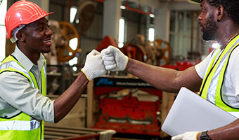 Two smiling warehouse employees share a fist bump in celebration.