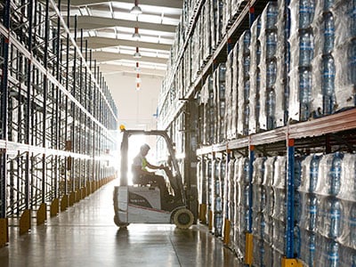 Forklift drives down a warehouse aisle.