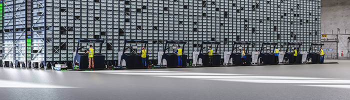An ASRS set up in a warehouse; workers place picked bins from Opex Infinity system