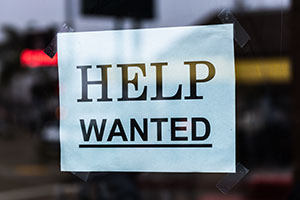 Computer printed help wanted sign taped to a window.