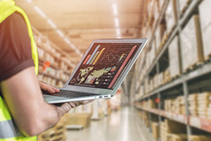 Warehouse manager uses a laptop to look at a report.