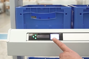 Order picker's hand presses a pick to light button after fulfilling an order