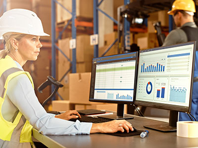 Warehouse manager reviews metrics on computer screens.