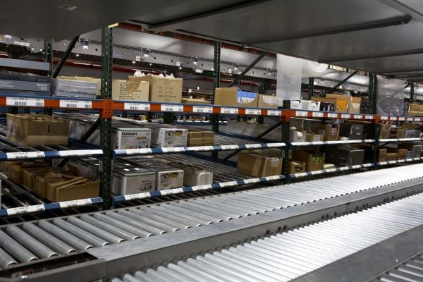 A pick module system with multiple conveyors next to shelves of product