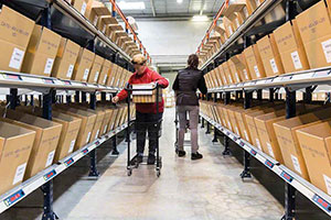 Two warehouse workers use a pick to light system to find what they are looking for.