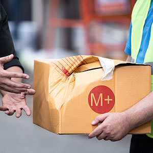 Worker holds a damaged box of inventory.