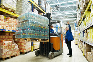 A worker drives a forklift with a loaded pallet.