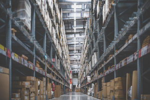 An aisle in a warehouse with pallets and boxes stacked on pallet rack