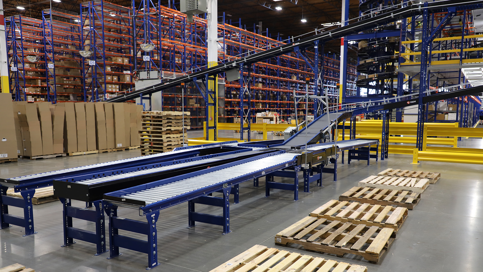 Automated conveyor in a warehouse with pallet rack system in the background