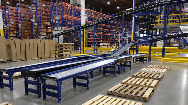 Automated conveyor in a warehouse with pallet rack system in the background