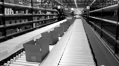 Pick module system in a warehouse with boxes on conveyor and gravity flow rack
