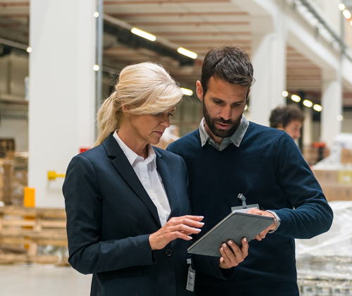 Employees check over a warehouse equipment list on a tablet
